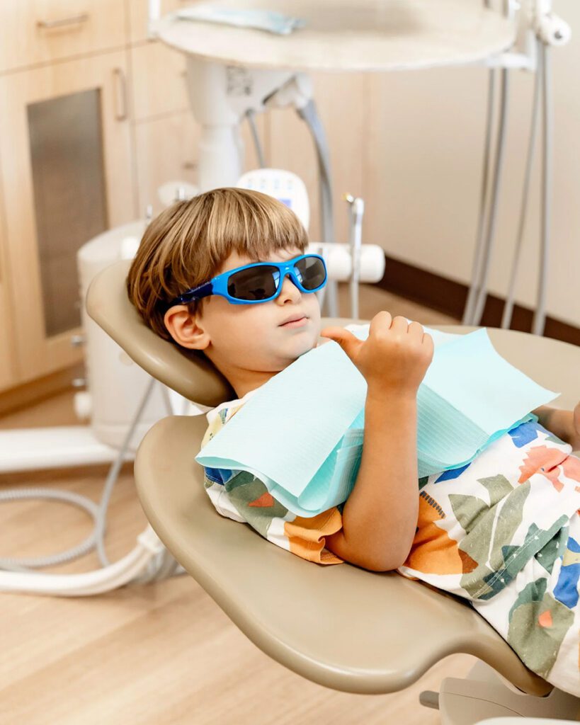 Child relaxing in dental chair during pediatric dental procedure